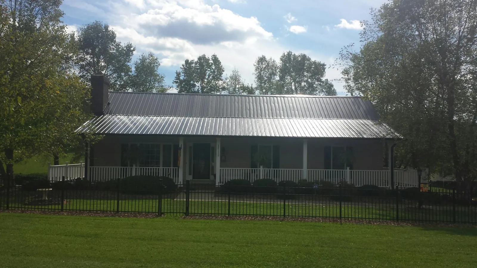 Gray metal roof on a brick ranch with a full width front porch — Gutter Guard Installation work by our crew in Fredonia