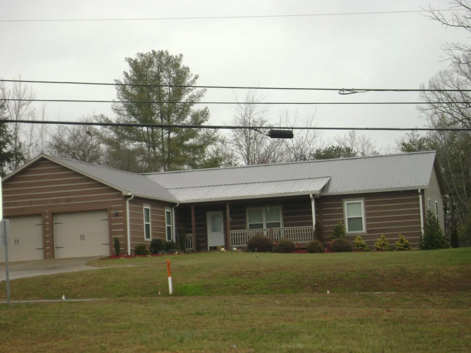 Gray metal roof on a log sided ranch home with a front porch in Fredonia