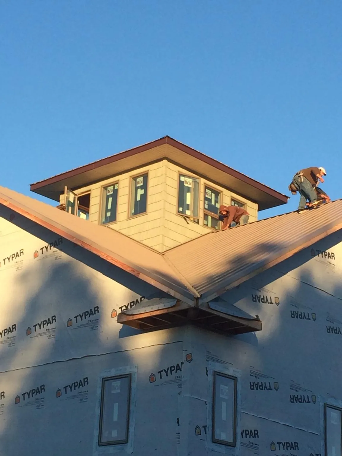 Roofers working around a rooftop cupola on a new metal roof at sunset — Roof Waterproofing in Fredonia by Roofing Brothers